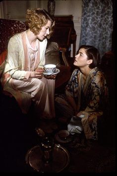 two women are sitting on the floor and one is holding a tea cup in her hand