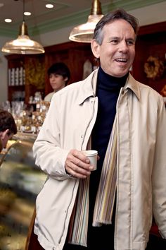 a man standing in front of a bar holding a coffee cup and looking at the camera