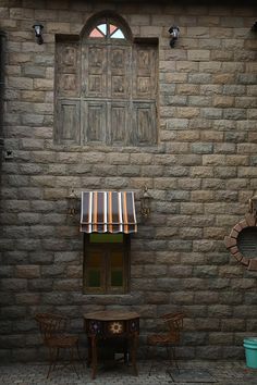 a table and chairs in front of a brick building with a window on the side