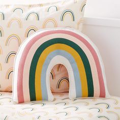 a pillow with a rainbow design on it and two pillows in the shape of an arch