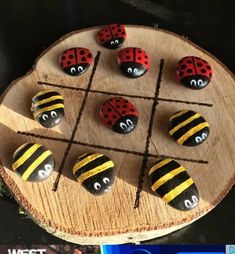 a wooden board topped with lots of rocks covered in painted ladybugs and bees