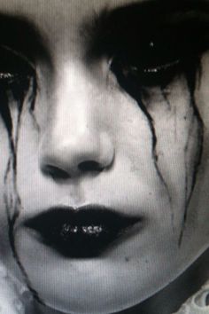 a woman's face with makeup and blood on it is shown in this black and white photo