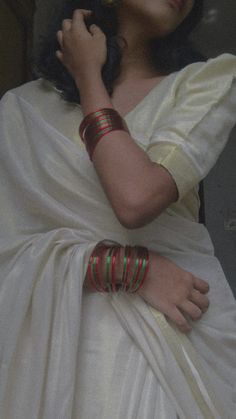 a woman in a white sari with bracelets on her arm