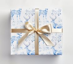 a gift wrapped in blue and white paper with a gold ribbon tied around the bow