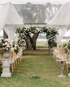 an outdoor wedding setup with white drapes and flowers