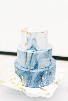 a three tiered blue marble cake with gold leaf decoration