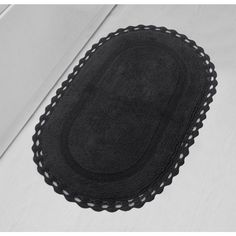 an oval black rug on top of a white tablecloth with scalloped edges