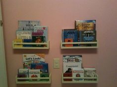 three shelves with books on them against a pink wall in a child's room