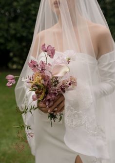 a woman wearing a veil holding a bouquet of flowers