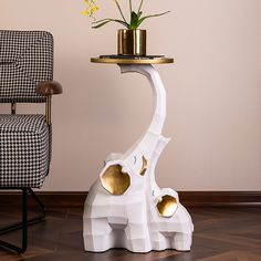 a white table with gold accents and a giraffe shaped side table next to a chair