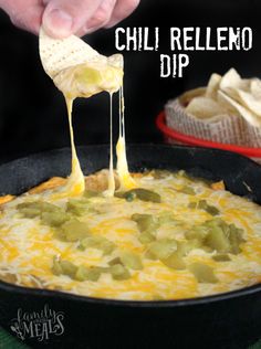 a person dipping cheese into a skillet filled with chili relleno dip