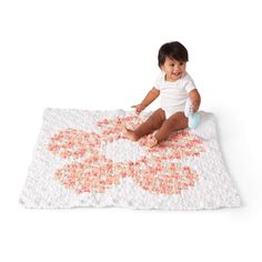 a small child sitting on top of a white and pink rug next to a bottle