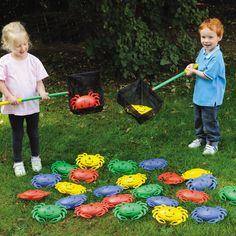 two young children playing with plastic crab toys in the grass, one holding a bat