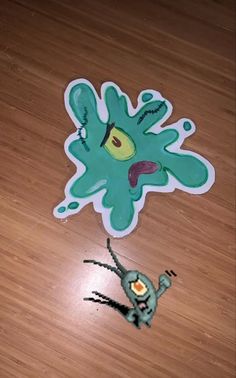 an odd looking sticker on the floor next to a small toy figure that looks like a monster