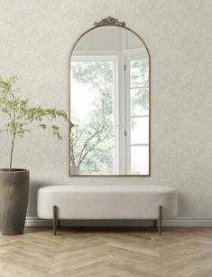 a white bench sitting in front of a mirror on the wall next to a potted plant