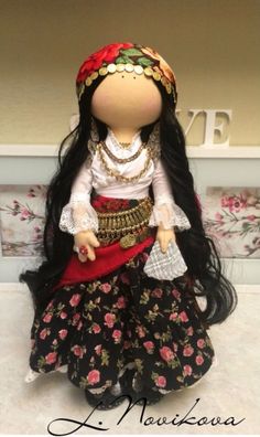 a doll with long black hair wearing a dress and headpiece, sitting on top of a table