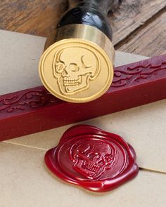 a wax stamp with a skull on it sitting next to a wax seal and envelope