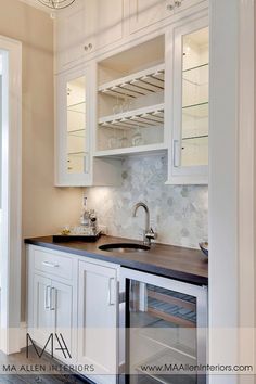 a kitchen with white cupboards and black counter tops is pictured in this image, there is also a wine rack above the sink