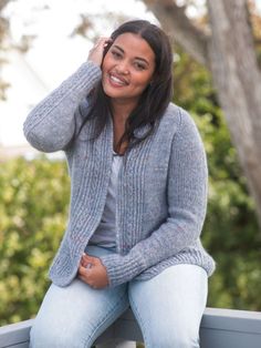 a woman sitting on top of a wooden bench talking on a cell phone and smiling