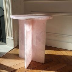 a pink table sitting on top of a hard wood floor next to a fire place