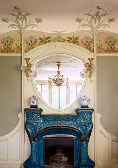 an ornate fireplace with a blue mantle and mirror above it, in front of a window