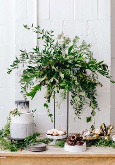 a table topped with lots of greenery next to a cake