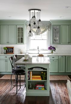 a kitchen with green cabinets and wooden floors