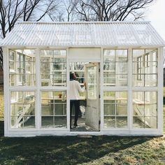 a woman standing inside of a white greenhouse