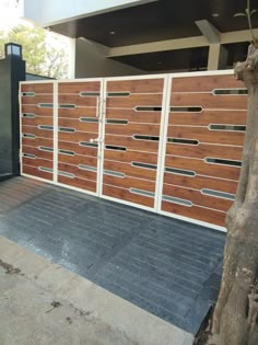 a large wooden gate with metal bars on the top and bottom part, in front of a house