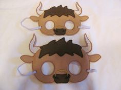 two masks made to look like cows with horns on their heads, one is brown and the other is black