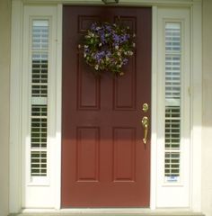 a red front door with shutters and a wreath on it