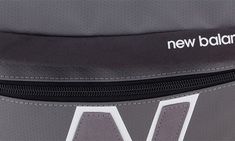 the new balance logo is on the side of a gray bag with white letters and black zippers