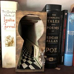 books are lined up on a shelf next to a wooden frame with an image of a man's head