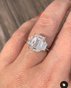 a woman's engagement ring with an emerald cut diamond in the center and side stones