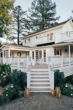 a white house with steps leading up to the front door and second story deck area