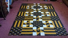 a large yellow and black quilt sitting on top of a purple floor next to a tv