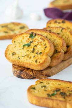 slices of bread with herbs on them sitting on a cutting board next to other pieces of bread