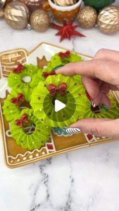 a person is pointing at some plants on a plate with other decorations in the background