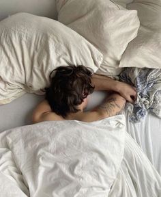 a man laying in bed with his head on the pillow