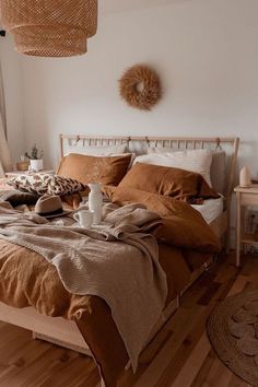 a bed with brown linens and pillows in a white room next to a window