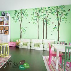 a living room with green walls and trees painted on the wall