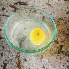 a glass bowl filled with liquid on top of a stone counter next to a yellow object