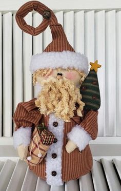 a stuffed santa clause holding a christmas tree ornament on top of a radiator