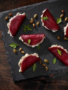 some food is laying out on a slate board with nuts and garnishes