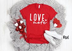 a red shirt with the words inspired rocks on it next to some shoes and flowers