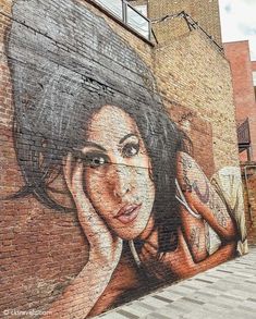 a brick wall with a painting of a woman on it