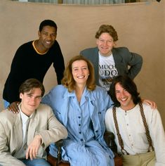 four people posing for a photo in front of a wall