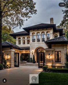 a large white house with lots of windows and lights on the front door is lit up at night