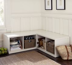 a corner bench with baskets and bottles on it in a room that has white paneling