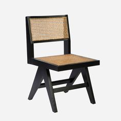 a black chair with wicker seat and back rests against a white background in the foreground